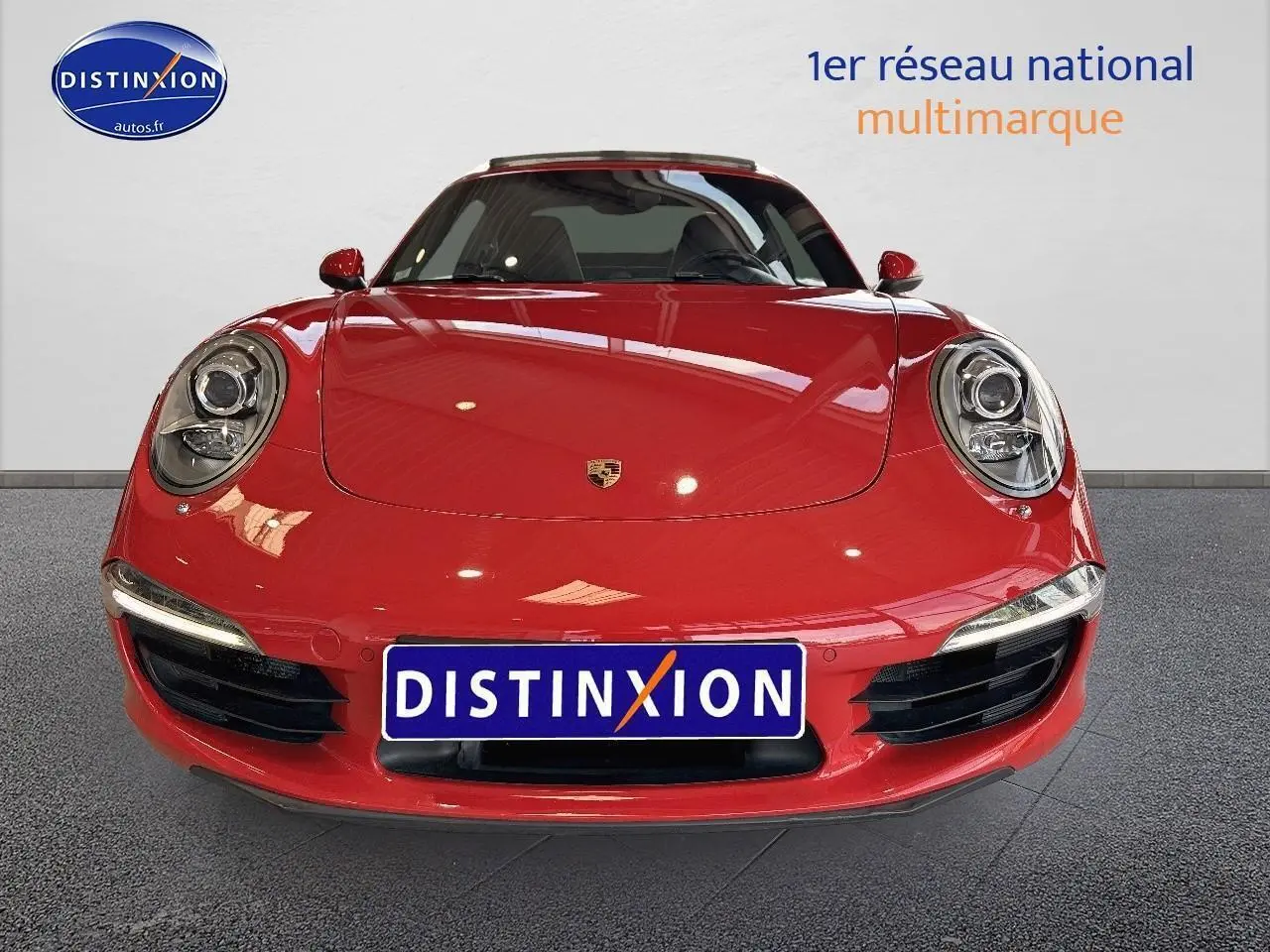 Vue frontale d'une Porsche 911 (991) Carrera 4 PDK rouge avec phares ronds et plaque Distinxion.