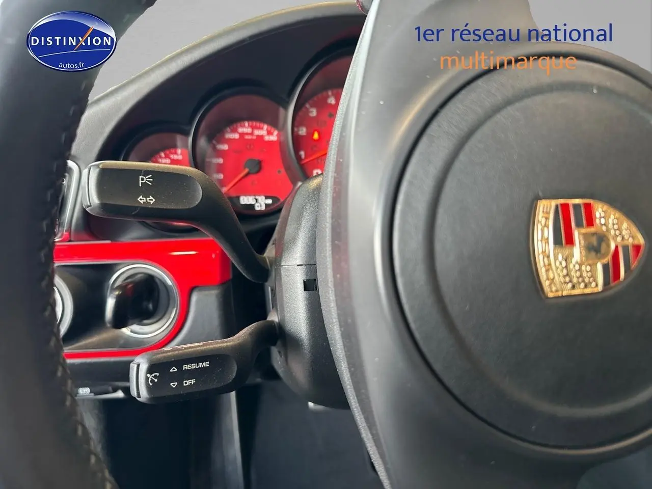 Gros plan sur le volant Porsche avec cadrans rouges et insert rouge brillant du tableau de bord d'une 911 Carrera 4 PDK rouge.