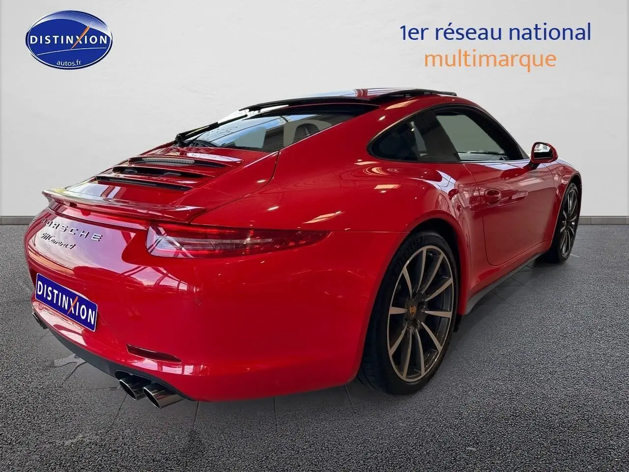 Vue 3/4 arrière droite d'une Porsche 911 Carrera 4 rouge avec échappement sport et jantes alu foncées.