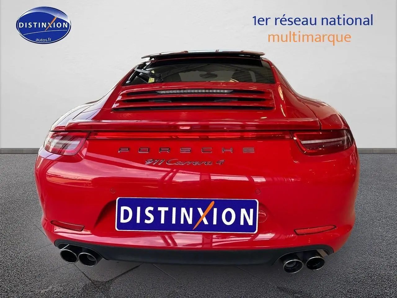 Vue arrière d'une Porsche 911 Carrera 4 rouge avec échappement sport et becquet arrière visible.