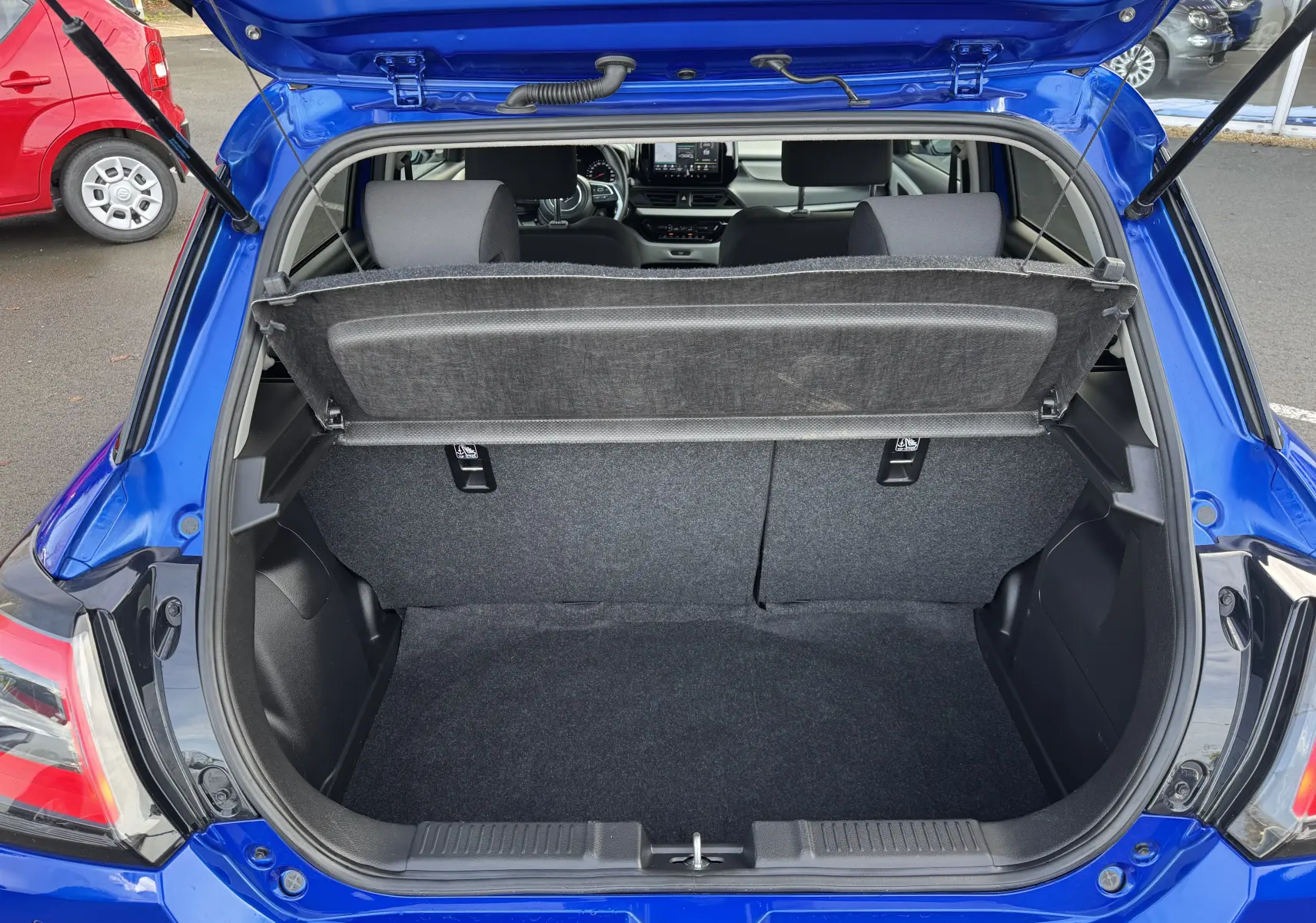 Coffre ouvert vu de l'arrière d'une Suzuki Swift bleu 2025, montrant l'espace de chargement et l'intérieur du véhicule.