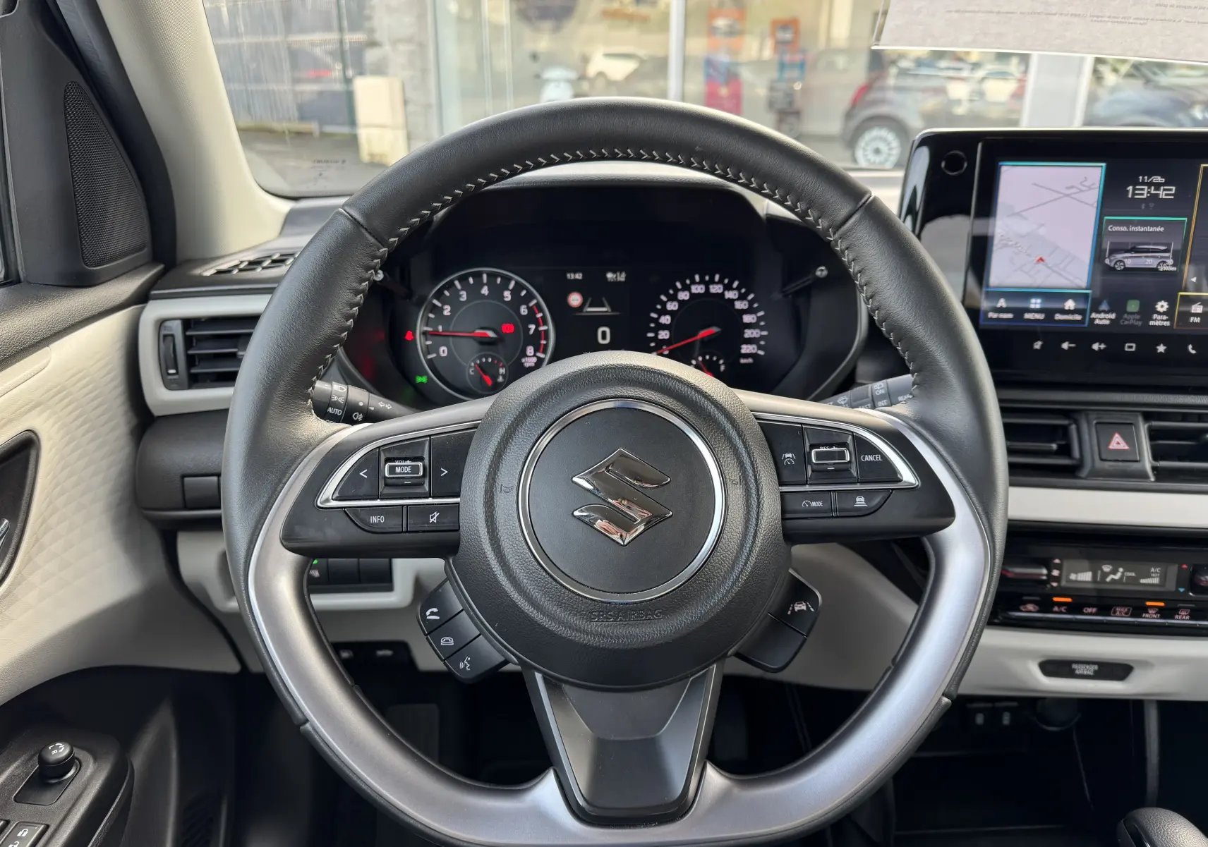 Vue centrée sur le volant de la Suzuki Swift 1.2 Hybrid Privilege Auto 2025, tableau de bord et écran tactile visibles.