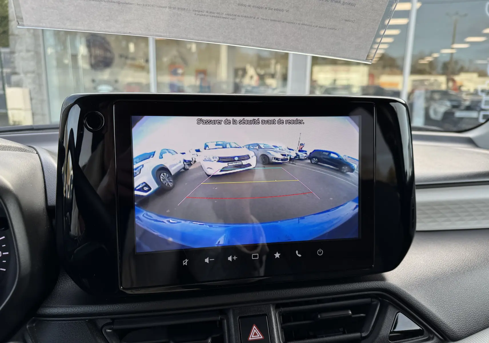 Écran central affichant la caméra de recul d'une Suzuki Swift bleue, vue arrière avec lignes de guidage colorées.