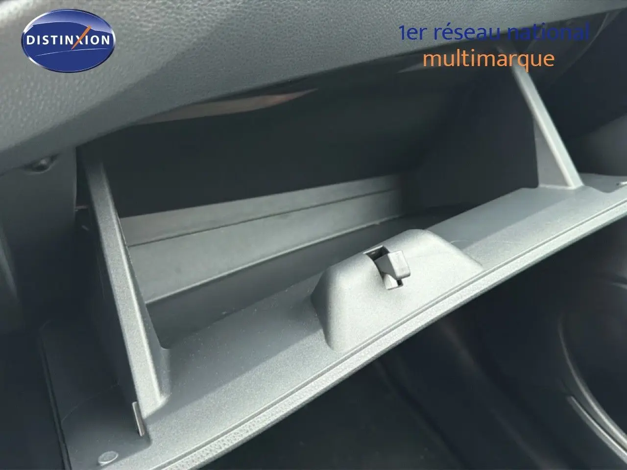 Gros plan sur la boîte à gants ouverte de la Toyota Aygo X noire, intérieur en plastique gris sombre.