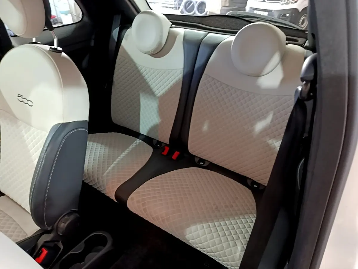 Vue intérieure sur la banquette arrière beige et noire de la FIAT 500 Hybrid 2021, avec détails matelassés et appuie-têtes ronds.