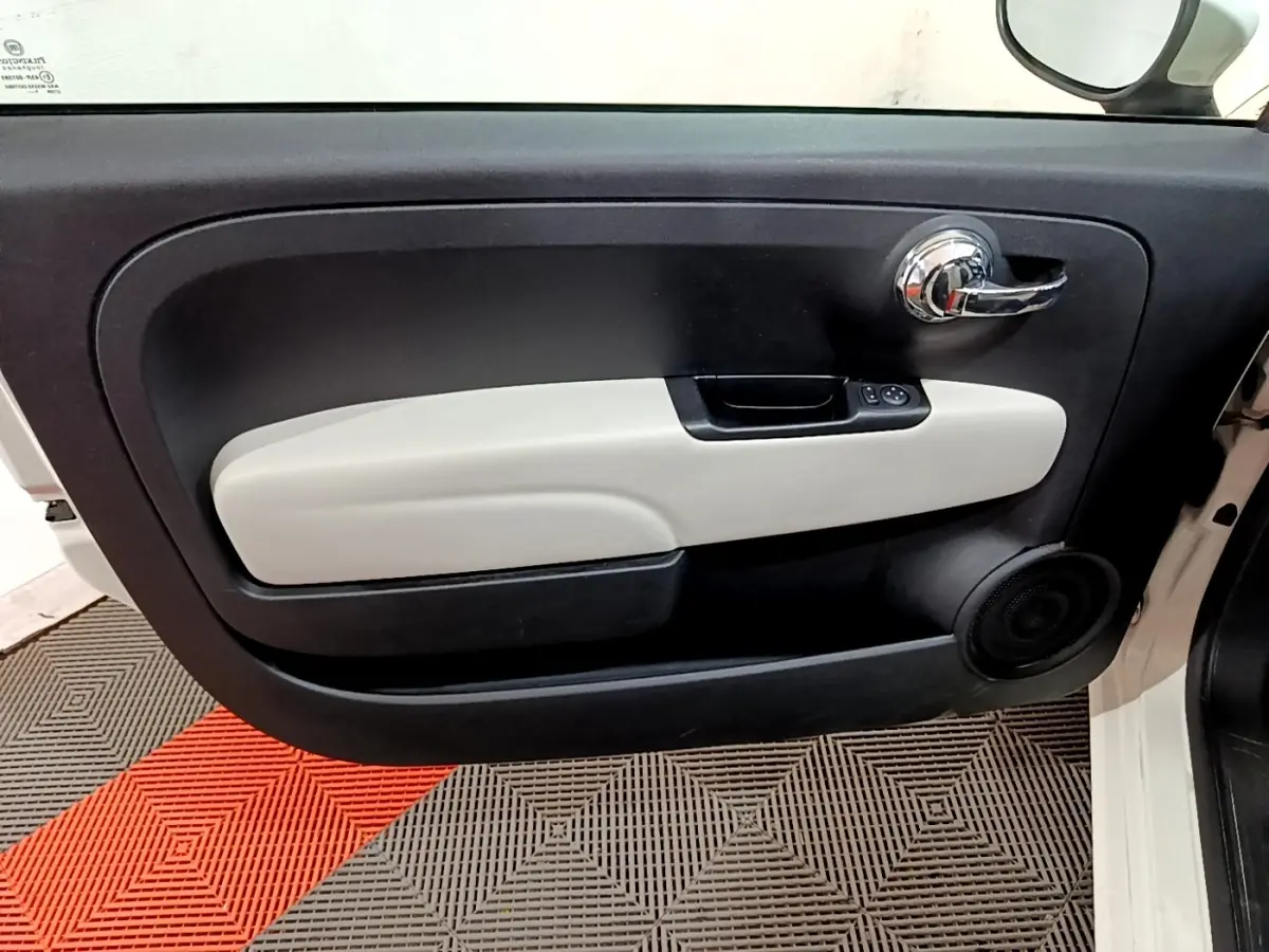 Vue rapprochée de la porte avant droite blanche de la FIAT 500 Dolcevita avec garniture intérieure bicolore noire et beige.