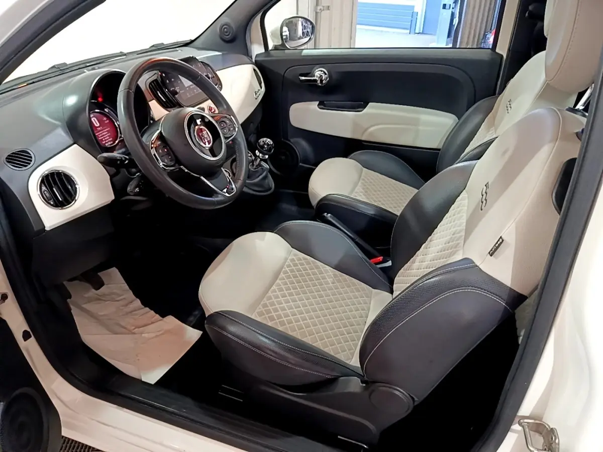 Vue intérieure côté conducteur de la Fiat 500 Dolcevita 2021, sièges cuir bicolores beige et noir, volant multifonctions.