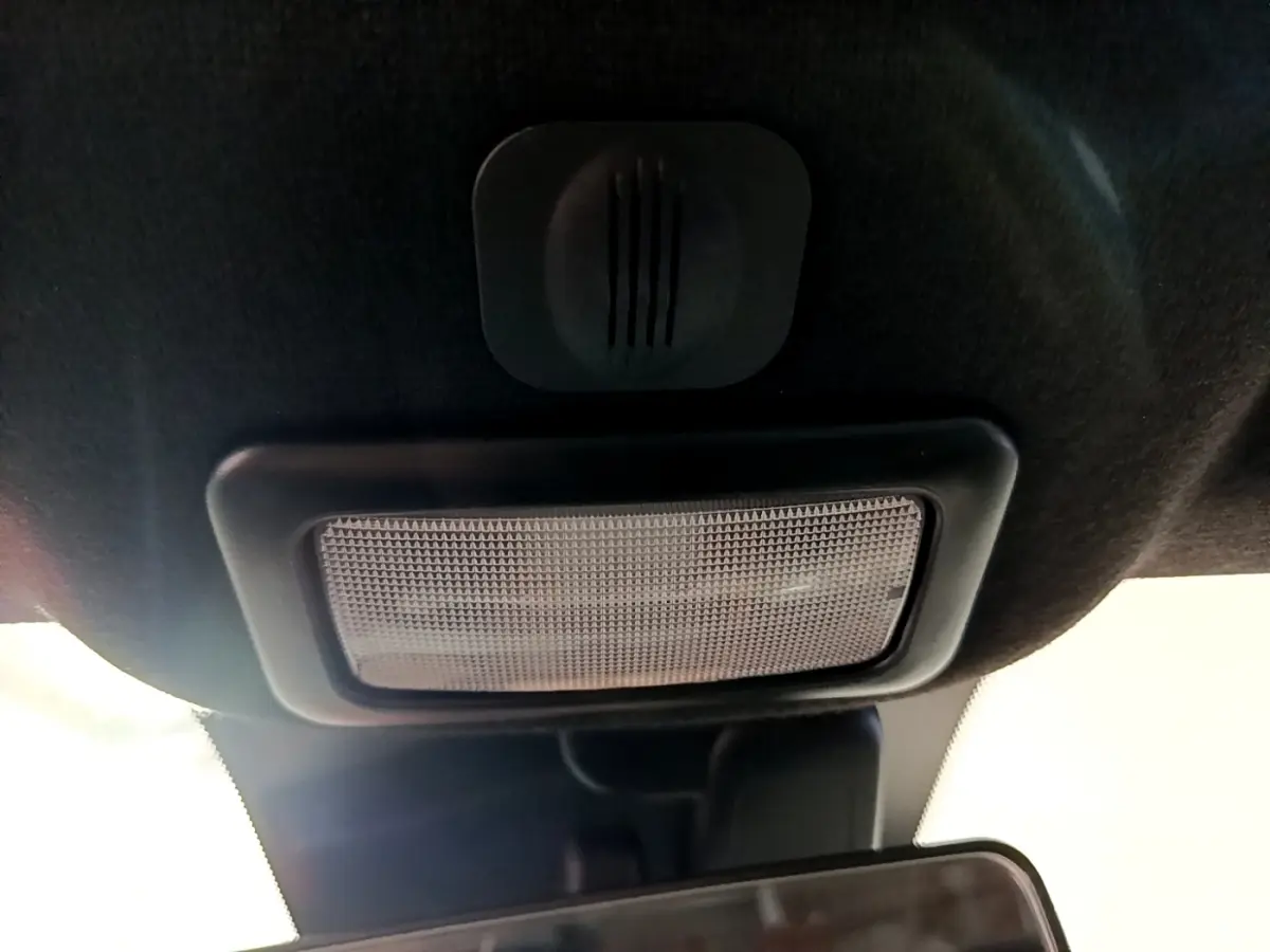 Plafonnier intérieur noir vu de dessous dans une Fiat 500 blanche, avec miroir de courtoisie partiellement visible.