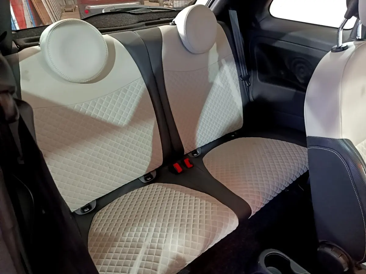 Vue intérieure montrant la banquette arrière beige matelassée de la Fiat 500 Hybrid 2021 avec appuie-têtes ronds.