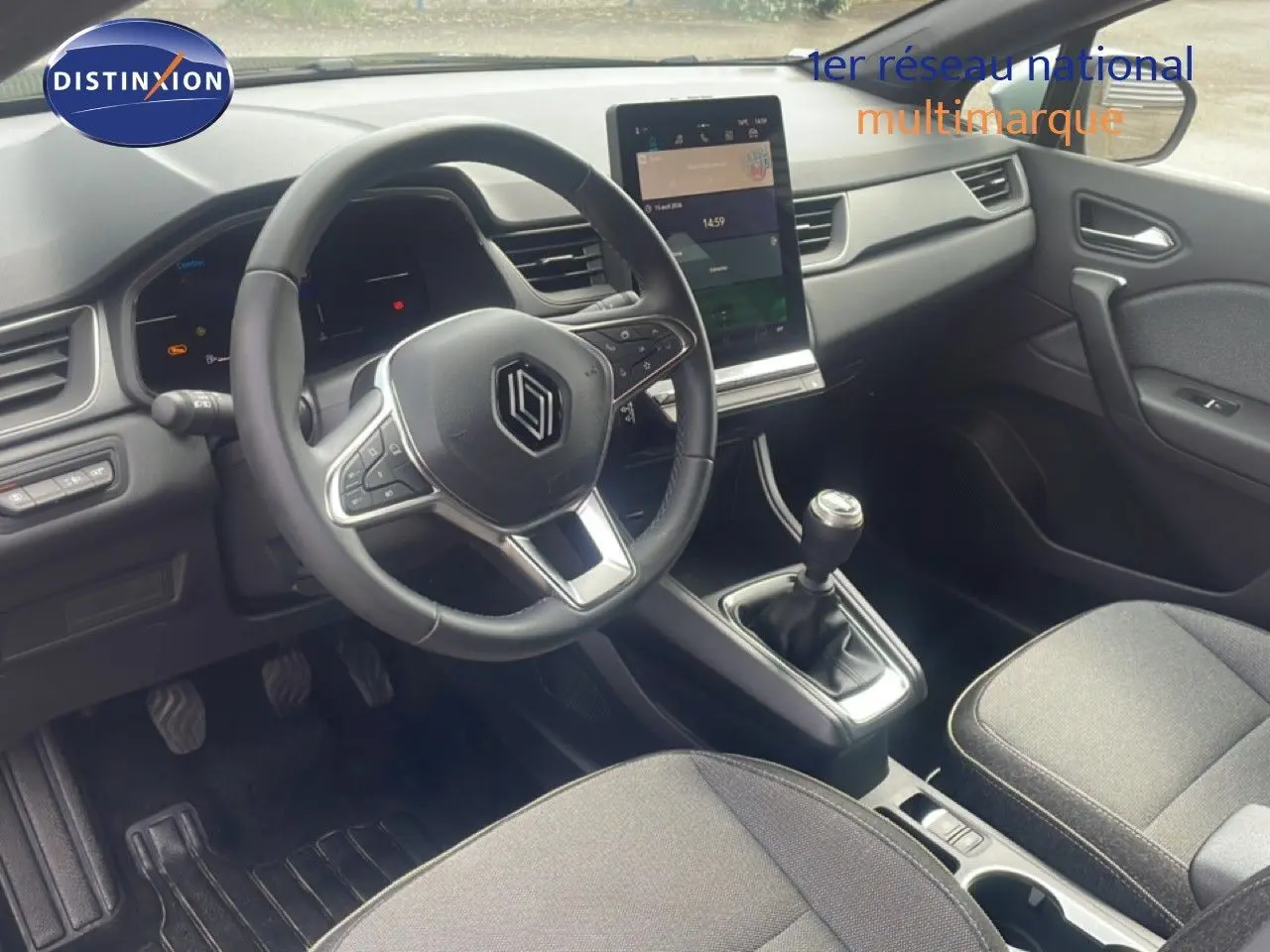 Vue intérieure avant droite du Renault Captur 2025, volant multifonction, écran tactile vertical et levier de vitesse manuel.