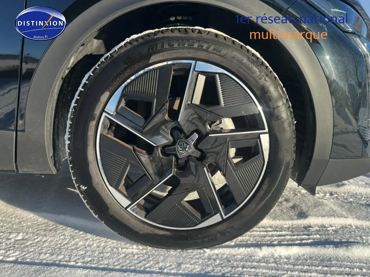 Gros plan sur la roue avant gauche noire de la Peugeot 408 Hybrid 145 GT e-dcs6 avec jante alu design moderne.