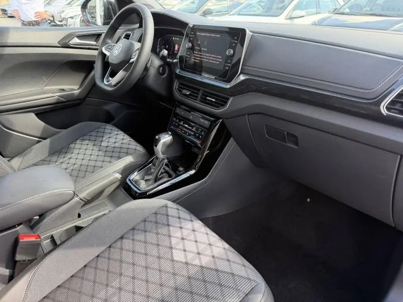Intérieur du Volkswagen T-Cross 2026 en vue côté passager, avec sièges tissu R-Line gris/noir et console centrale moderne.
