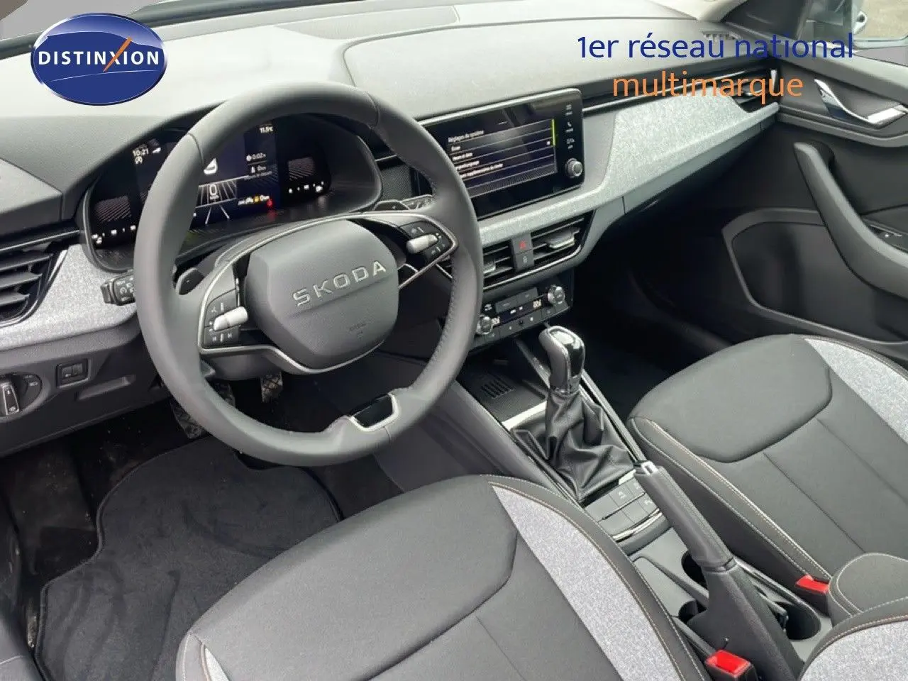 Intérieur de la Skoda Kamiq 2025 vu côté conducteur, tableau de bord moderne et sièges tissu gris noir.