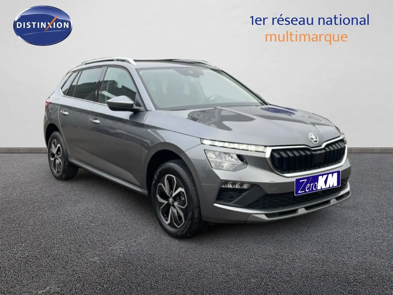 Vue 3/4 avant droit d'un Skoda Kamiq gris graphite métallisé avec calandre noire et jantes bi-ton.