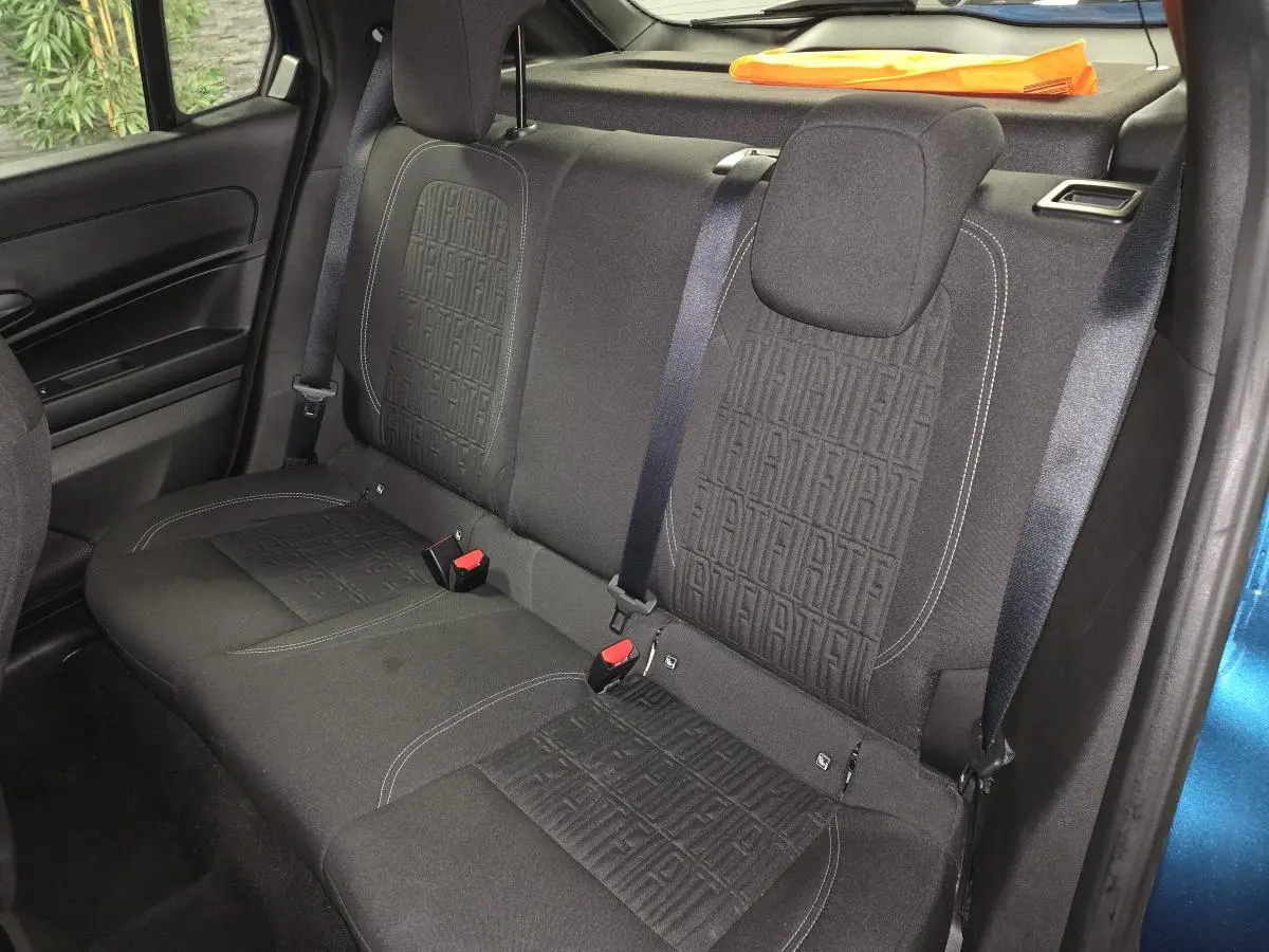 Vue intérieure sur la banquette arrière noire avec motifs FIAT, ceinture et partie de la portière bleu métallisé visible.