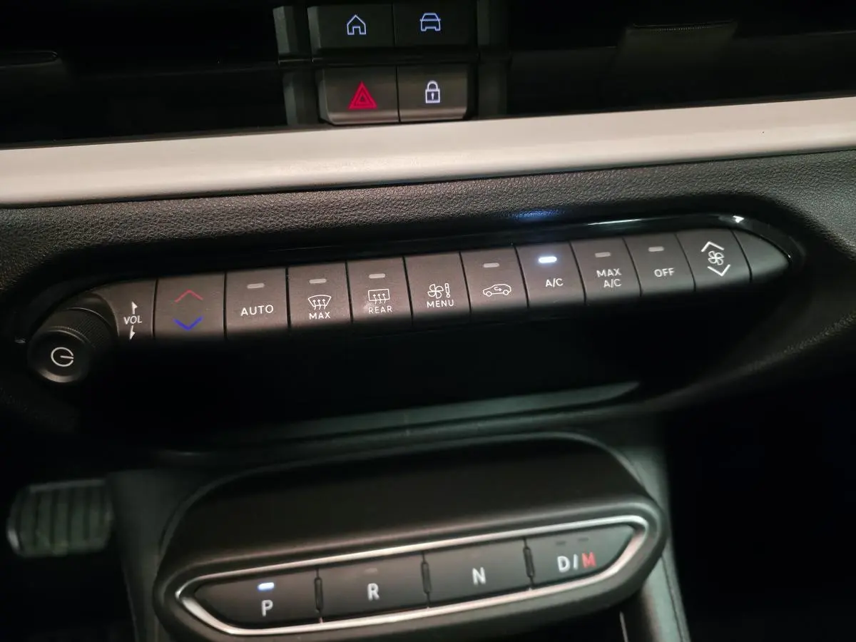 Vue rapprochée du tableau de bord de la FIAT 600 hybride 2024, montrant les commandes de climatisation et la boîte automatique.