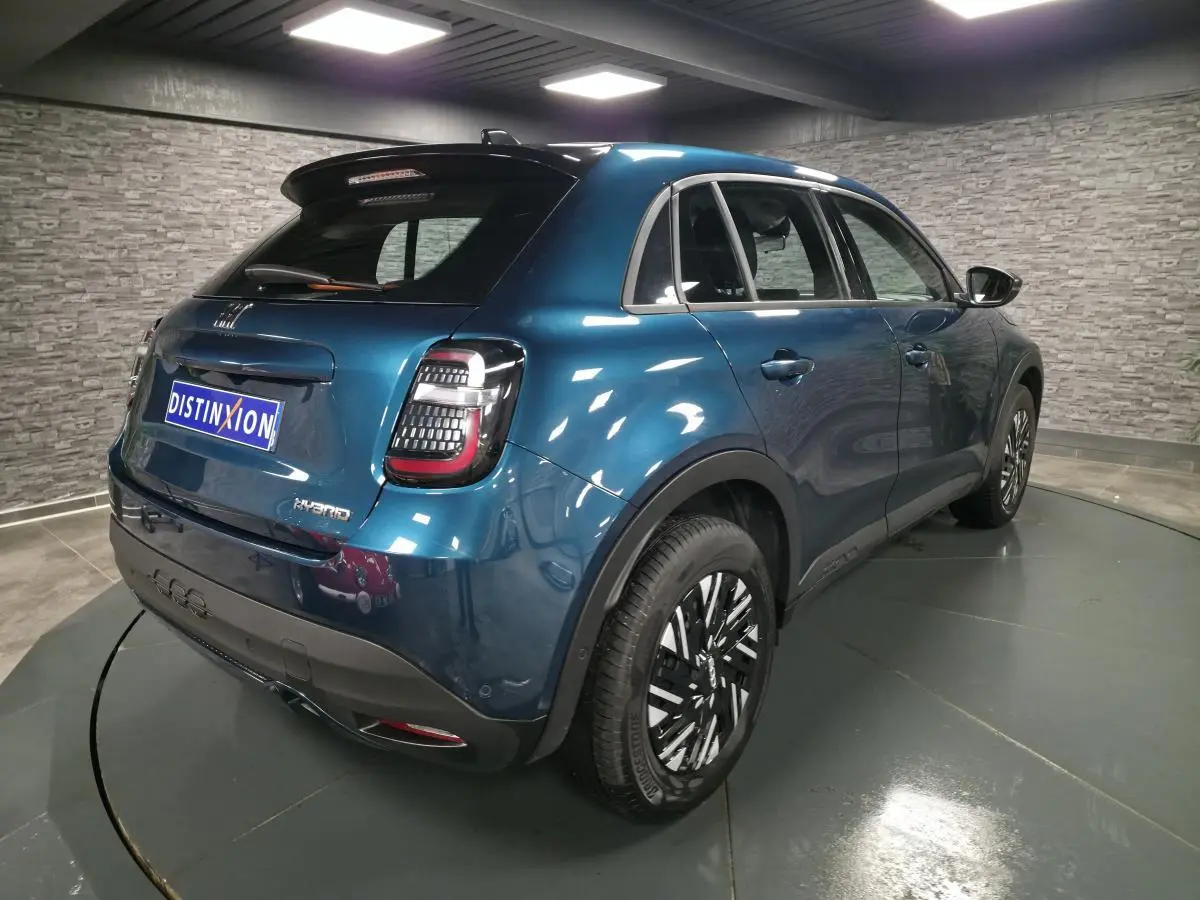 Vue 3/4 arrière droite d'une FIAT 600 Hybrid 2024 bleu métallisé avec feux arrière LED et jantes bicolores.