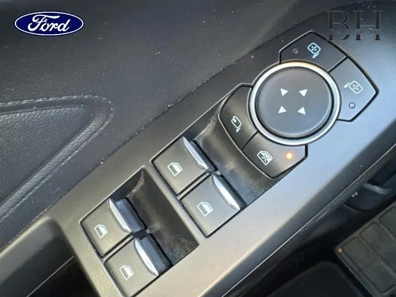 Détail des commandes de lève-vitres et réglages des rétroviseurs côté conducteur intérieur d'une Ford Focus gris lunaire 2020.