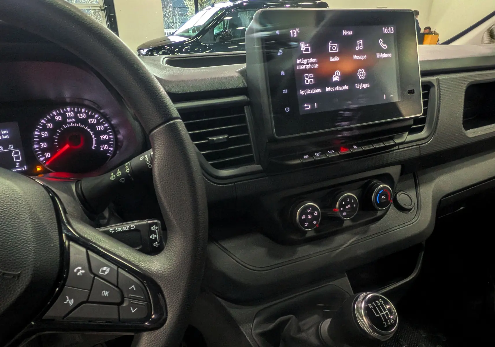 Vue intérieure côté conducteur du Renault Trafic Combi gris, montrant le volant, tableau de bord et écran tactile central.