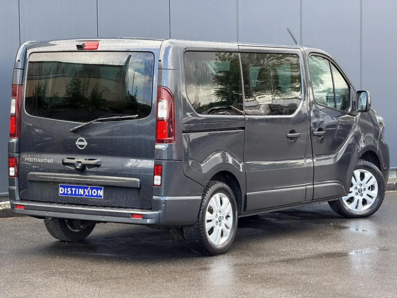 Vue 3/4 arrière droite du Nissan Primastar Combi gris comète avec hayon vitré et jantes alliage 17 pouces.