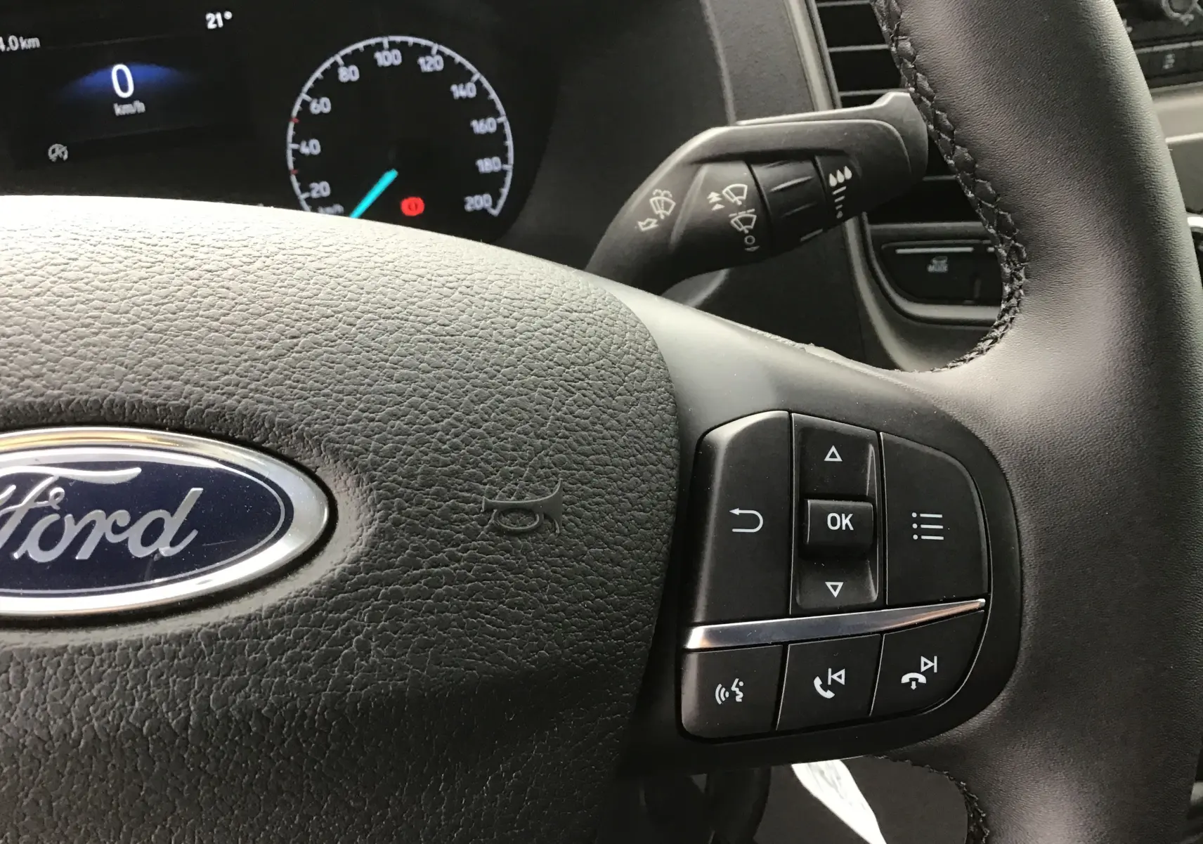 Gros plan sur le volant multifonction noir du Ford Transit Châssis Cabine 2024 avec commandes intégrées.