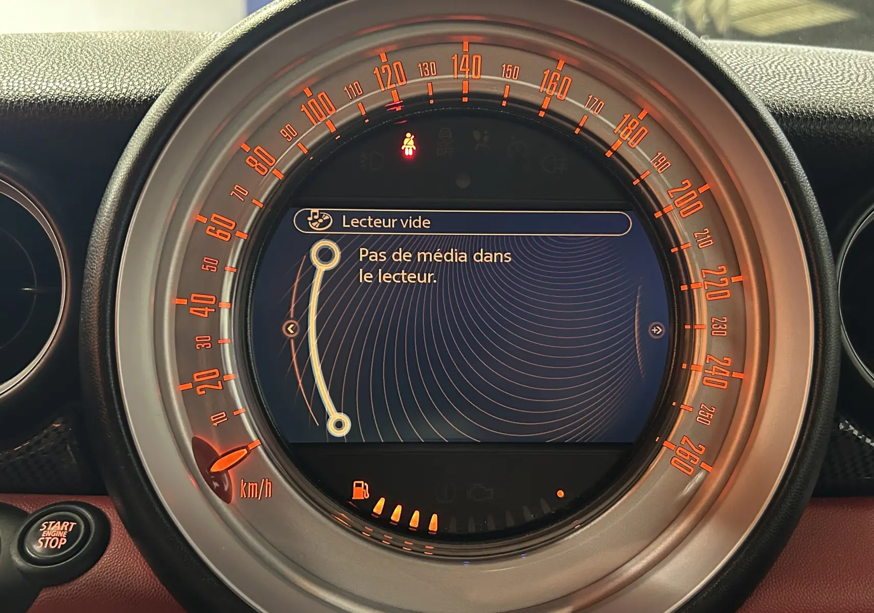 Vue rapprochée du compteur central du MINI Cabriolet rouge 2012, affichant un écran multimédia sans média inséré.