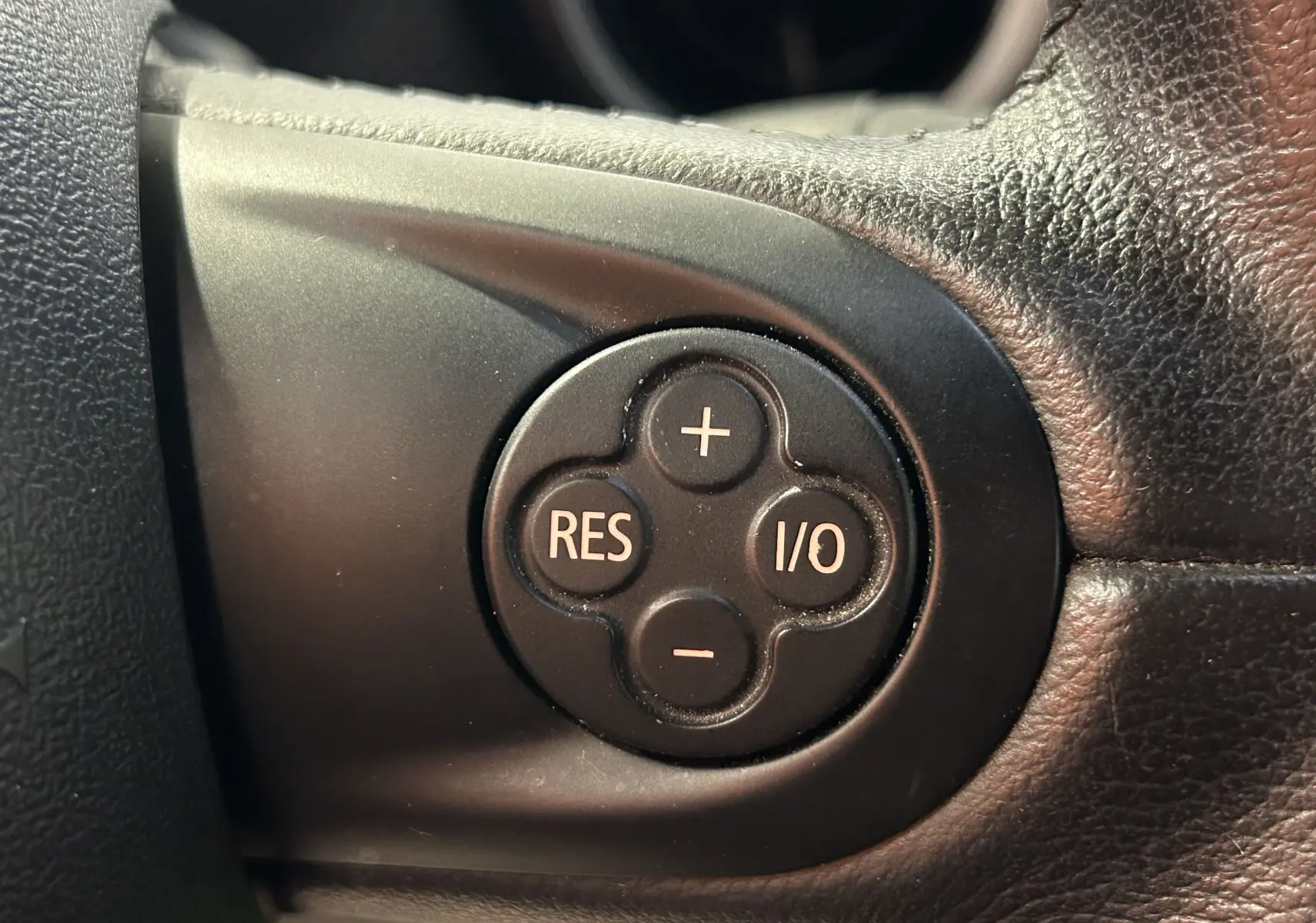 Gros plan sur les commandes de volume et téléphone au volant noir du MINI Cabriolet Cooper S rouge de 2012.