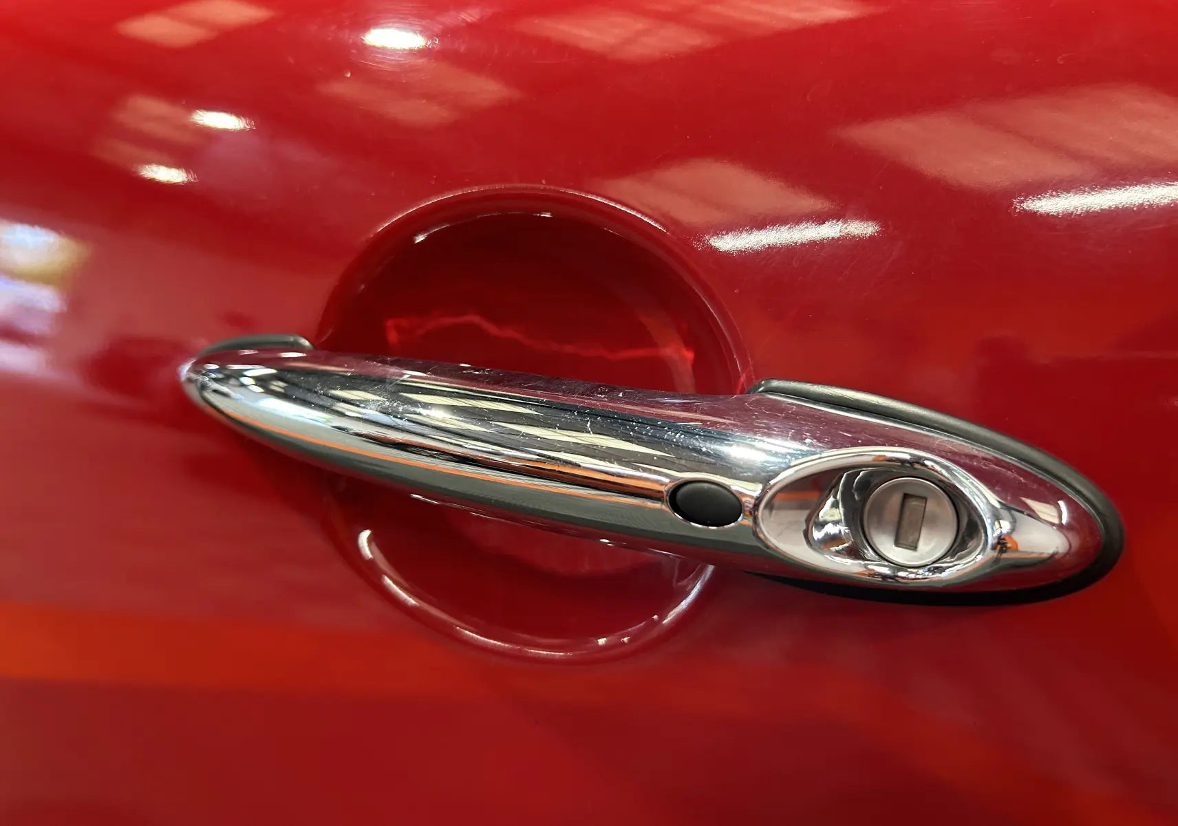 Vue plongeante sur le capot rouge vif d'une MINI Cabriolet Cooper S avec bandes blanches et logo MINI central.