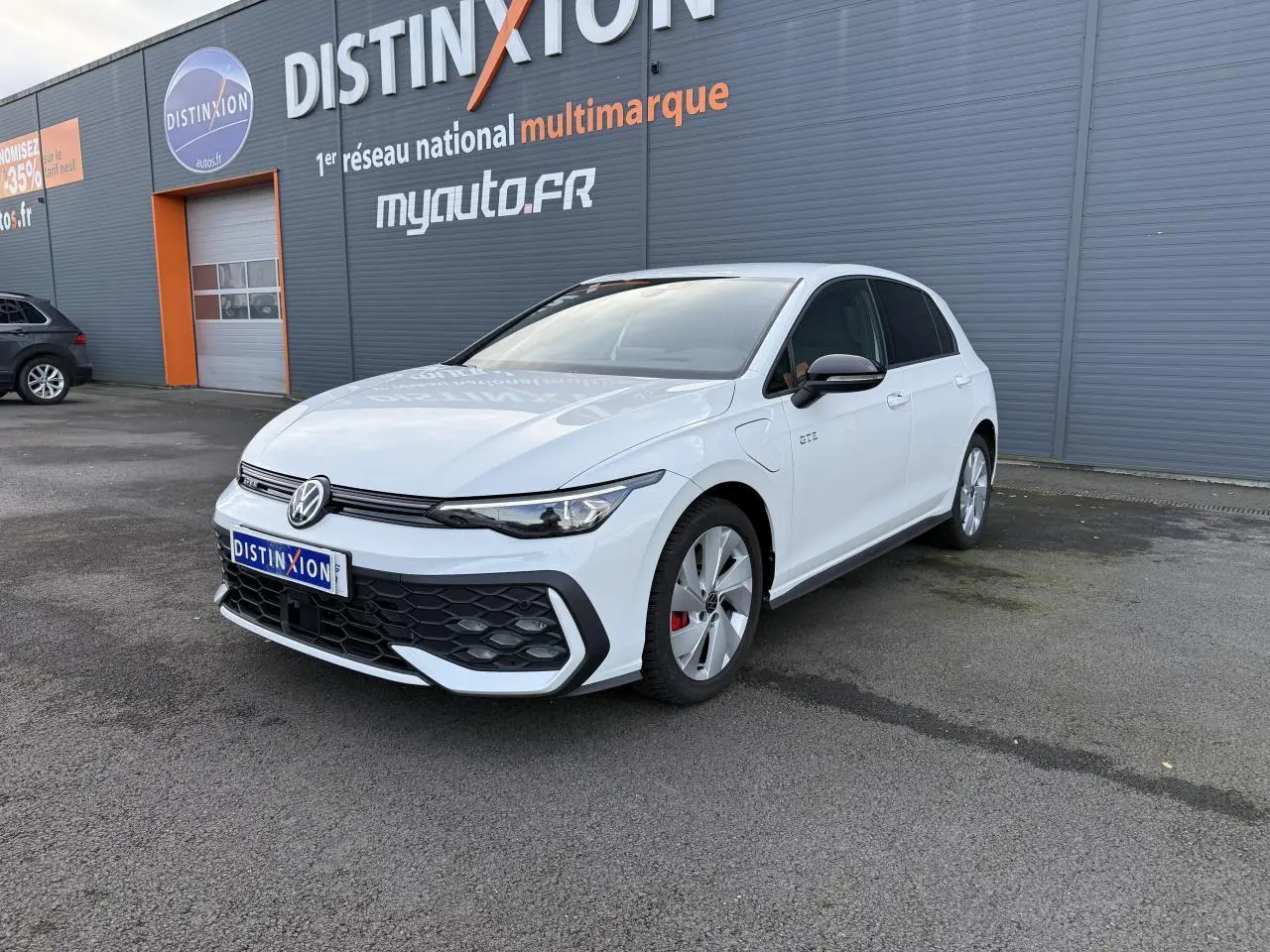 Volkswagen Golf 1.5 eHybrid blanc oryx nacré vue 3/4 avant avec calandre nid d'abeilles et jantes spécifiques GTE.
