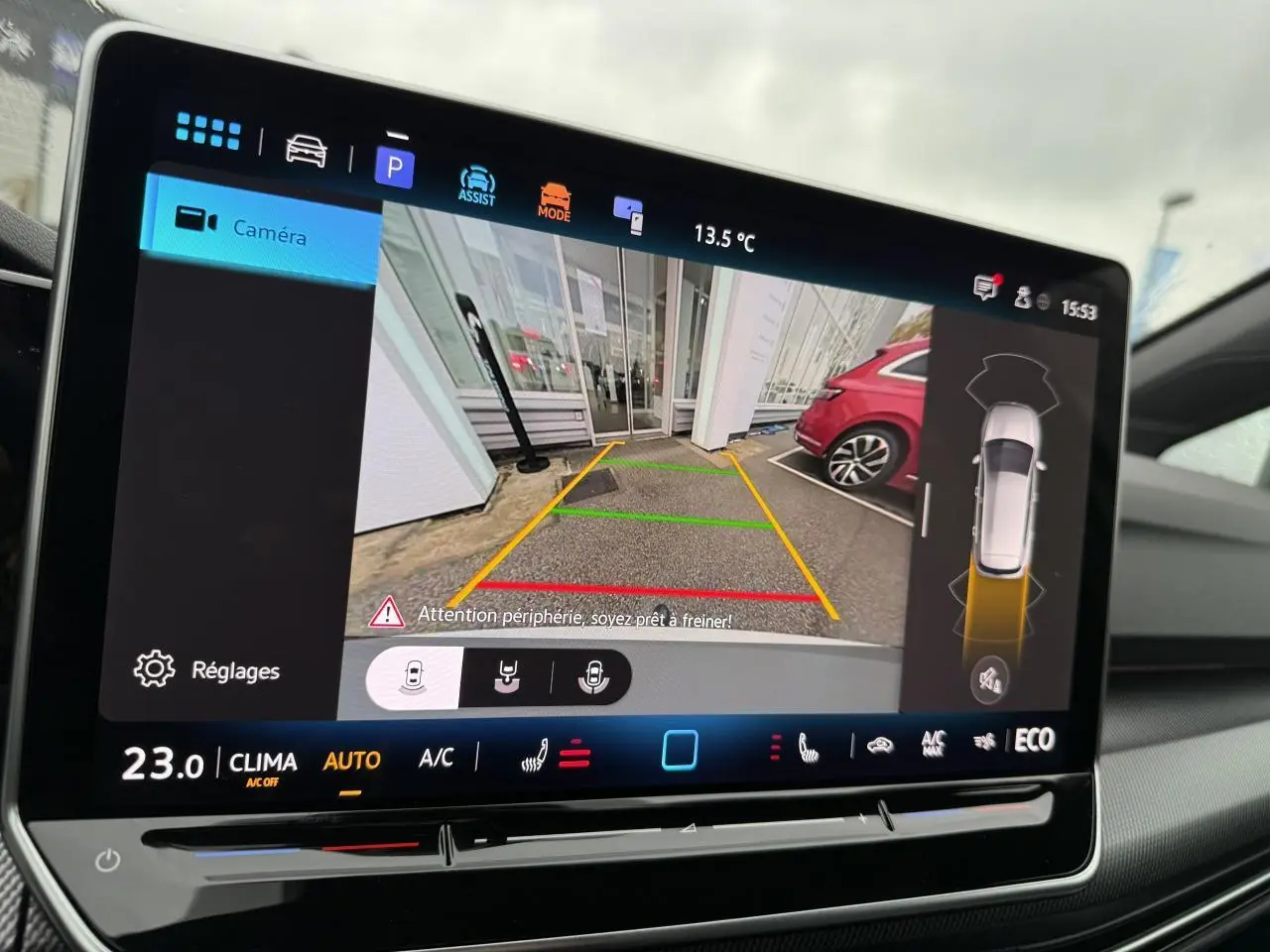 Écran central montrant la caméra de recul d'une Volkswagen Golf 1.5 eHybrid blanche, avec guidage de stationnement.