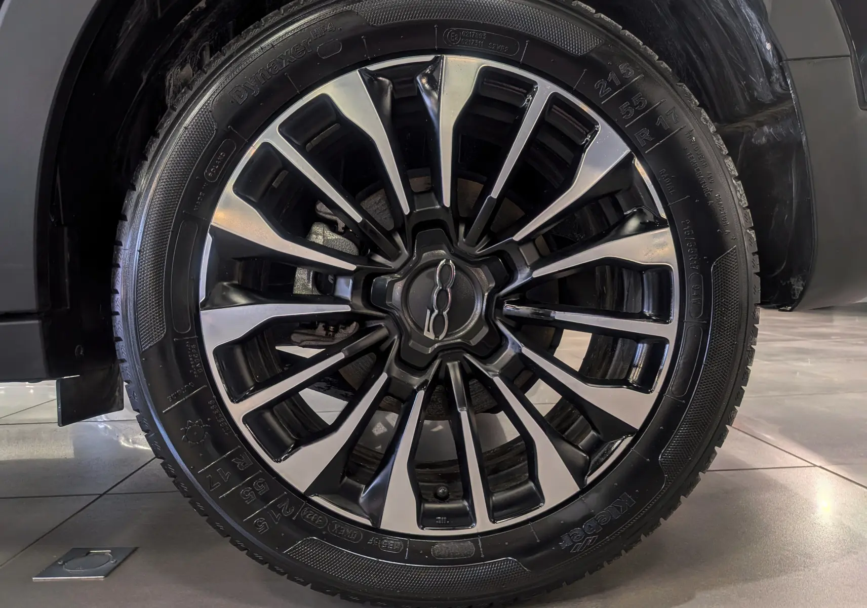 Gros plan sur la jante avant droite noire et argentée du FIAT 500X 2024 en Noir Cinéma.