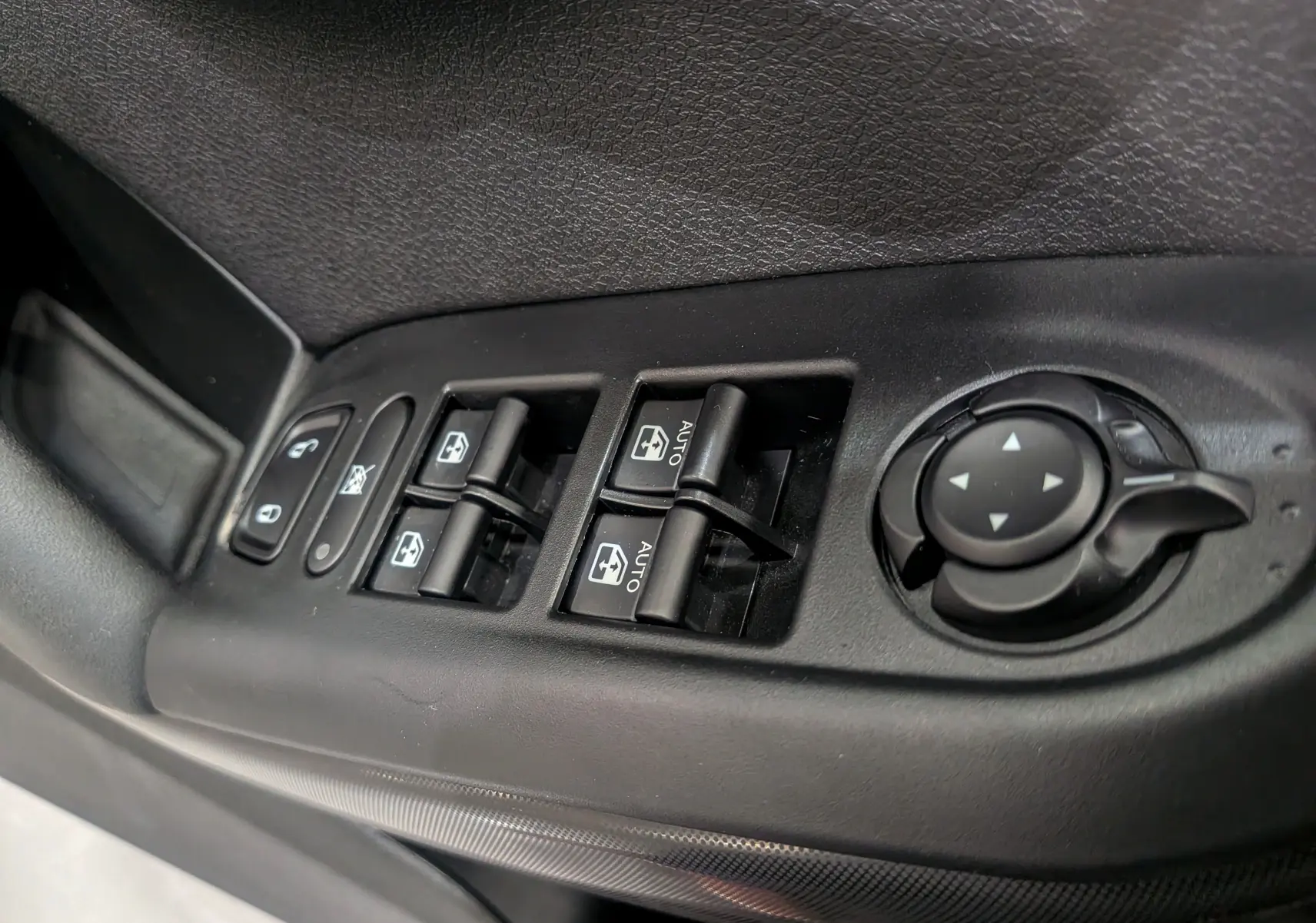 Gros plan sur les commandes de lève-vitres et réglage des rétroviseurs côté conducteur du Fiat 500X noir cinéma 2024.