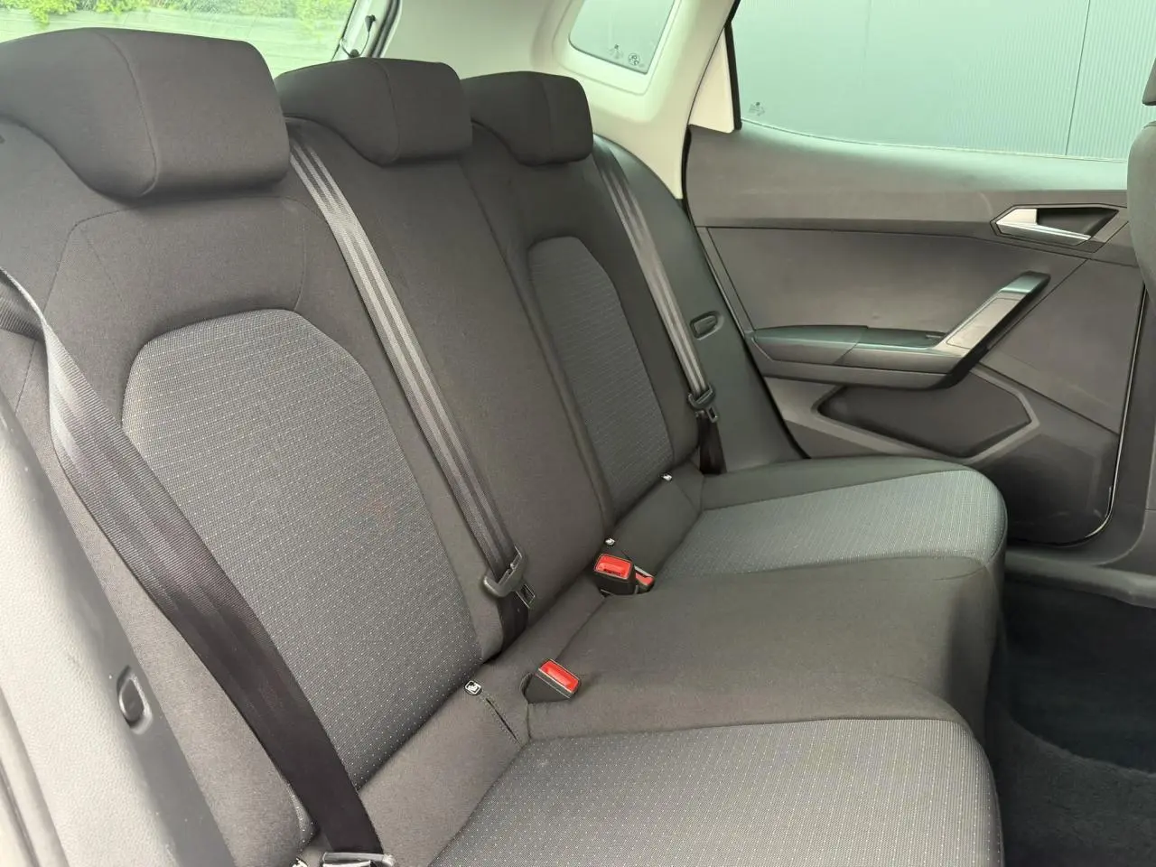 Vue intérieure du siège arrière droit de la SEAT Arona 2025, tissu gris foncé avec ceintures de sécurité visibles.