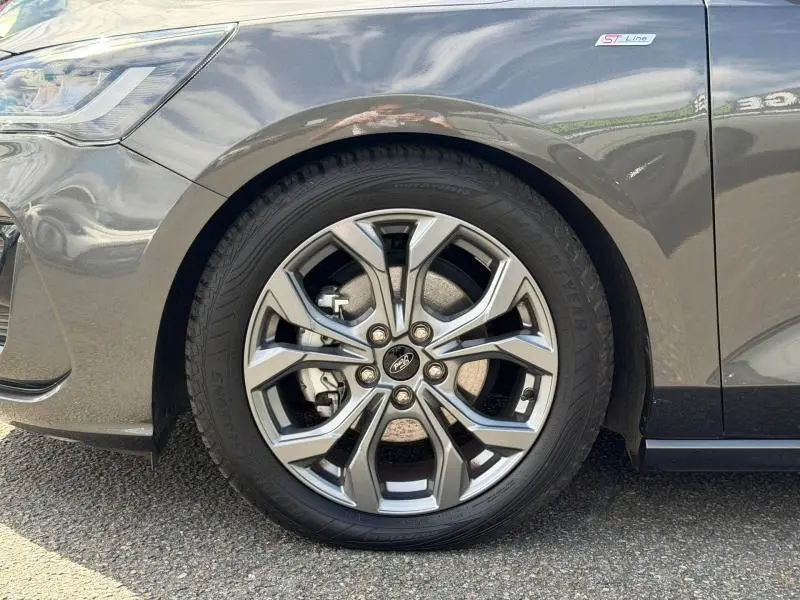 Gros plan sur la roue avant droite d’une Ford Focus gris lunaire métallisé avec badge ST-Line X visible sur l’aile.