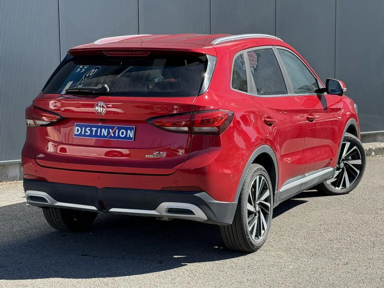 Vue 3/4 arrière droite du MG ZS 1.5 Hybrid+ 197 Luxury rouge Diamond avec jantes alliage et feux LED.