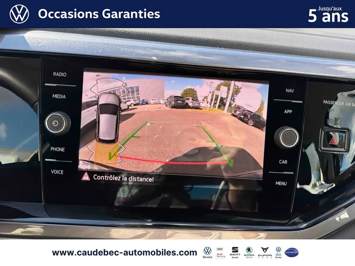 Écran tactile intérieur montrant la caméra de recul d'une Volkswagen Polo noire intense nacrée en stationnement.