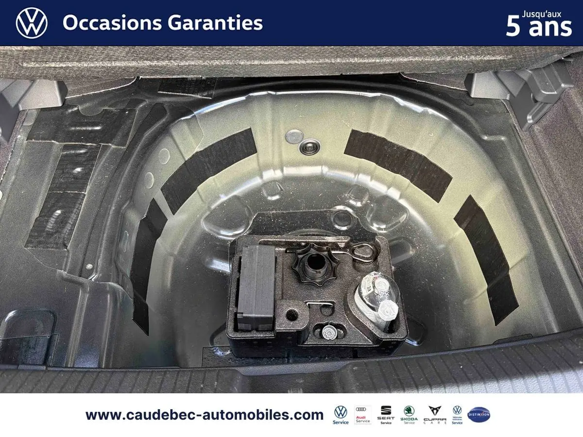 Coffre ouvert montrant la roue de secours et le kit de réparation sur une Volkswagen Polo noire intense nacrée.
