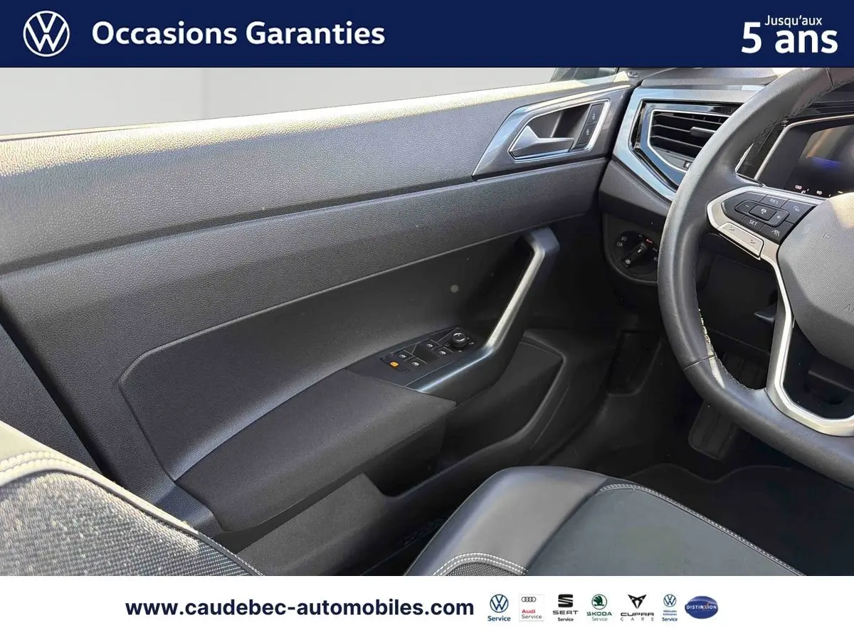 Intérieur côté conducteur de Volkswagen Polo noir intense nacré, montrant porte, volant cuir et siège partiel.