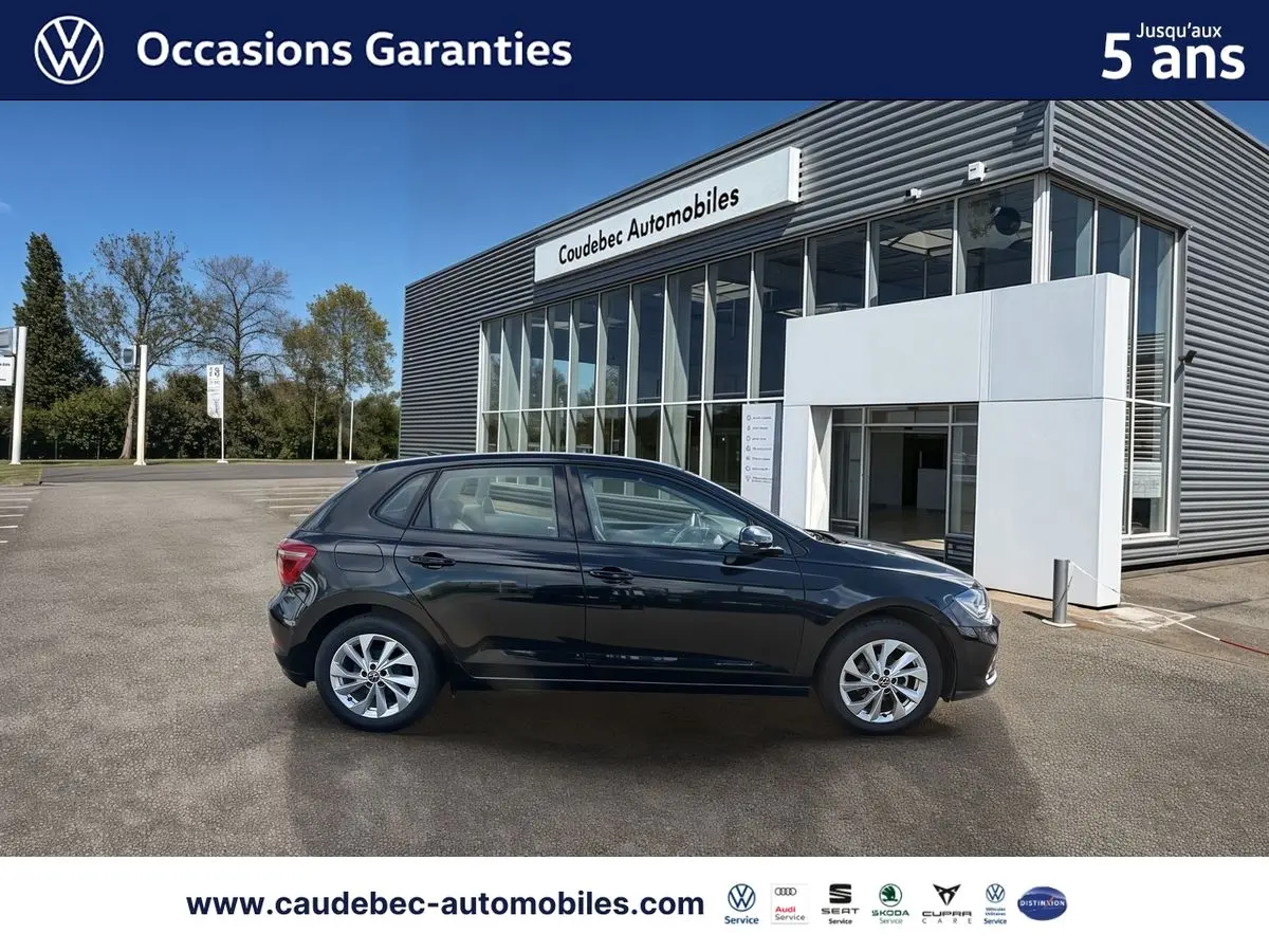 Profil gauche d'une Volkswagen Polo noire intense nacrée 2025, avec jantes alliage Palermo 16 pouces, devant un showroom.