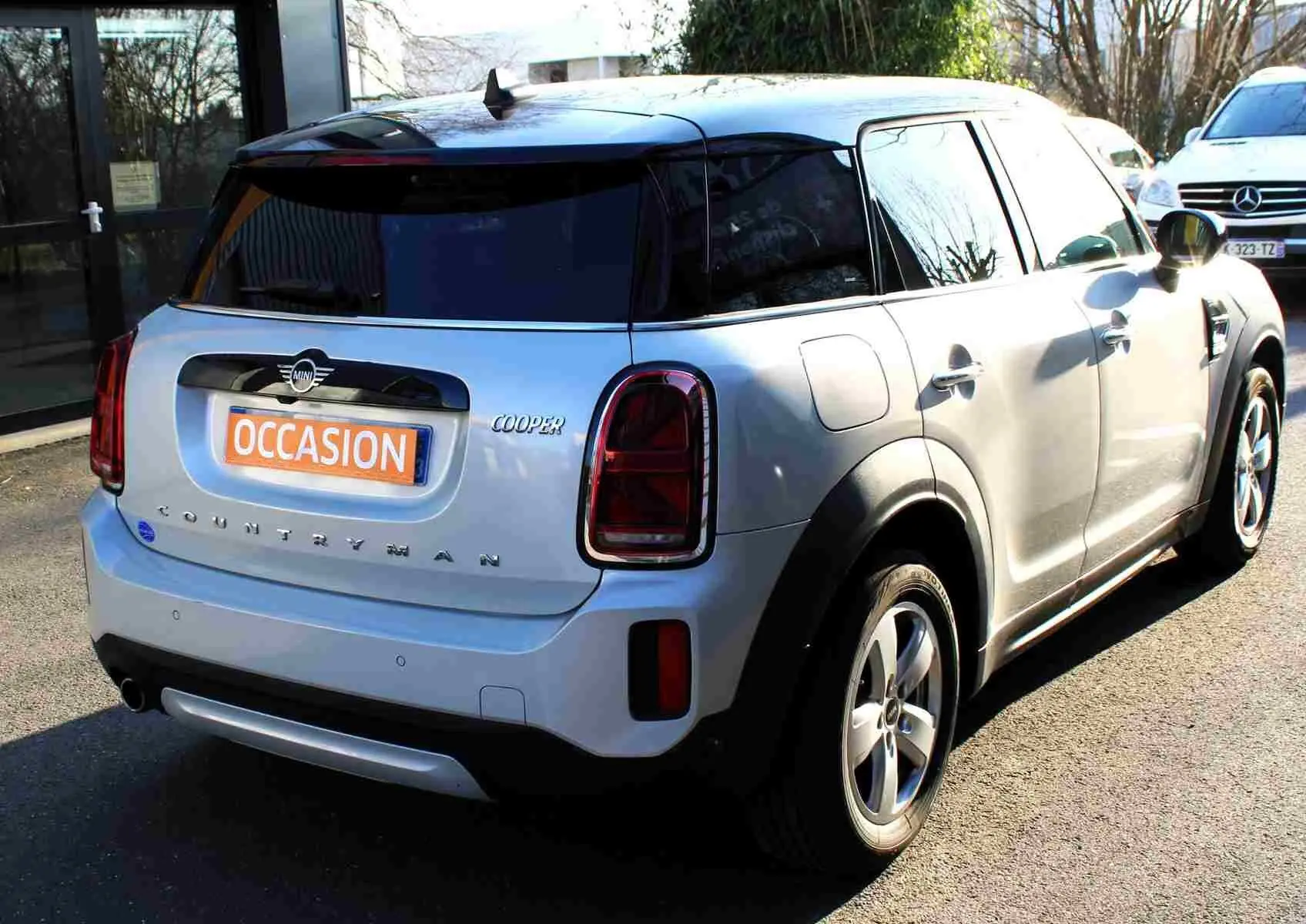 Vue 3/4 arrière droite d'une MINI Countryman gris perle métal avec toit noir et feux arrière foncés, en extérieur.