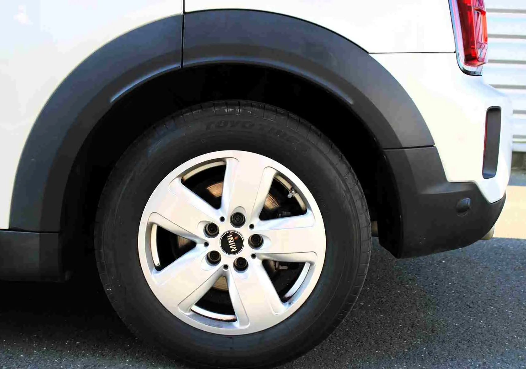 Gros plan sur la roue arrière droite d'une MINI Countryman gris perle avec jante argentée et entourage noir.