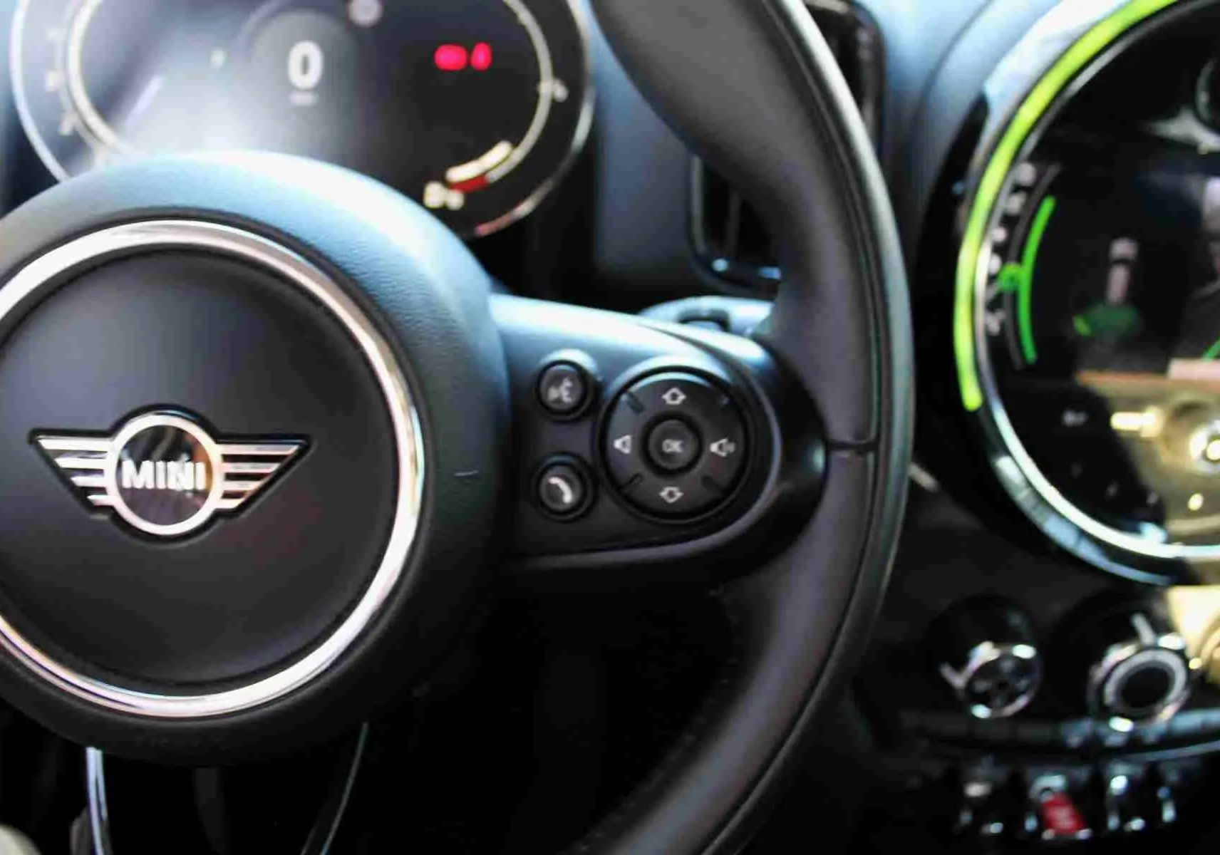 Gros plan sur le volant noir de la MINI Countryman II avec commandes intégrées et tableau de bord numérique partiellement visible.