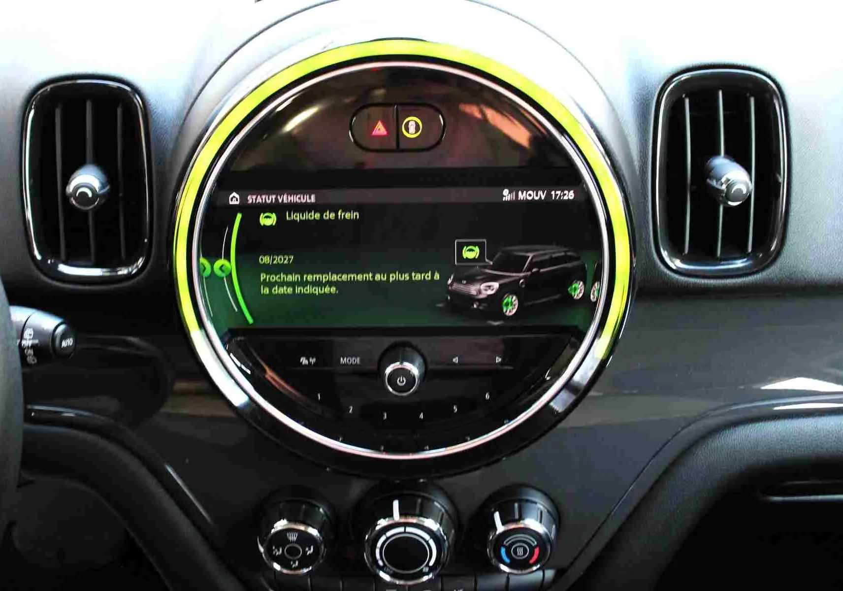 Vue rapprochée du tableau de bord de la MINI Countryman 2020, écran central rond avec affichage d'entretien et aérateurs noirs.