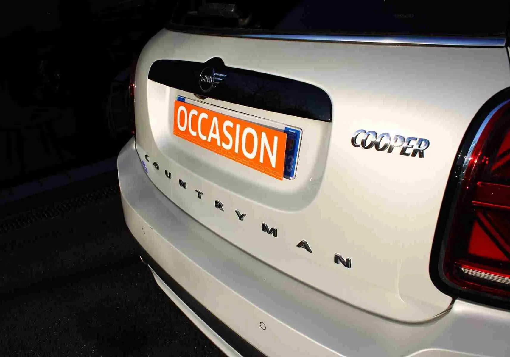 Vue arrière droite d'une MINI Countryman gris perle métal avec toit noir et badge Cooper visible.