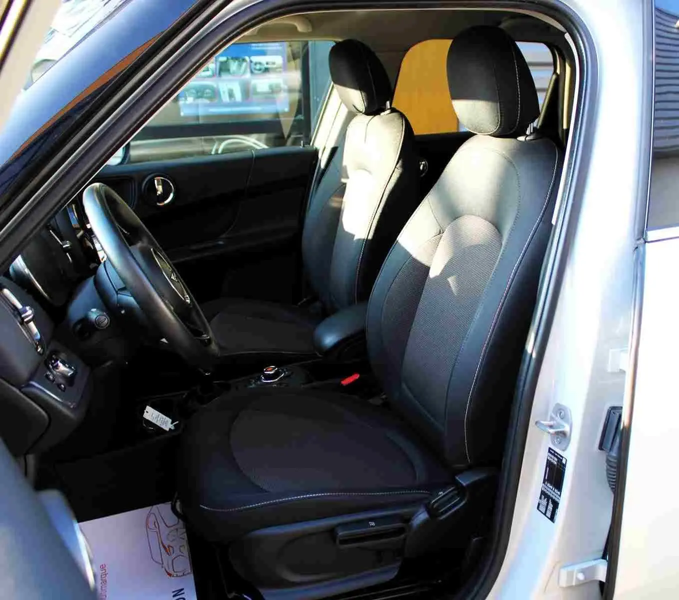 Vue intérieure côté conducteur du MINI Countryman gris perle avec sièges tissu noirs et volant cuir.