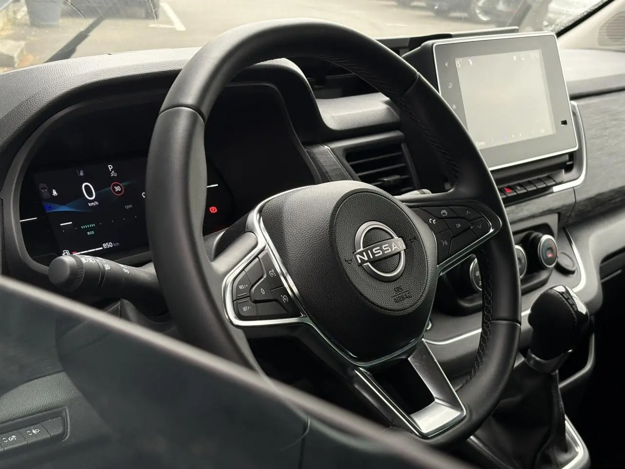 Vue rapprochée du volant et du tableau de bord numérique du Nissan Primastar 2025, intérieur noir moderne.