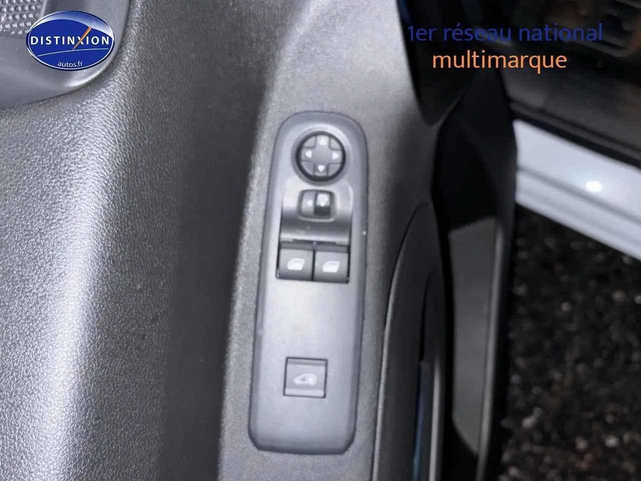 Gros plan sur la commande des vitres électriques côté conducteur du Citroën Berlingo Fourgon blanc, porte ouverte.