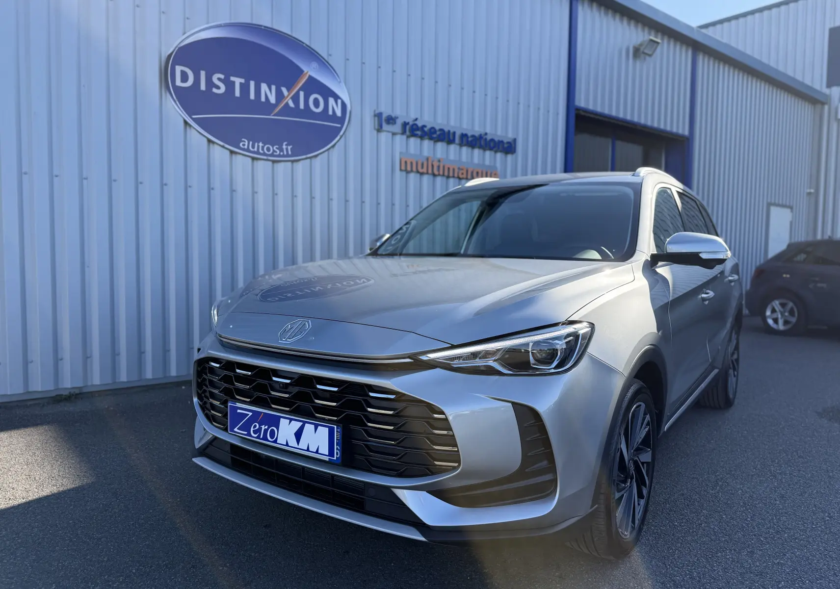 Vue 3/4 avant droite du SUV MG ZS gris Hampstead avec calandre imposante et phares LED distinctifs.