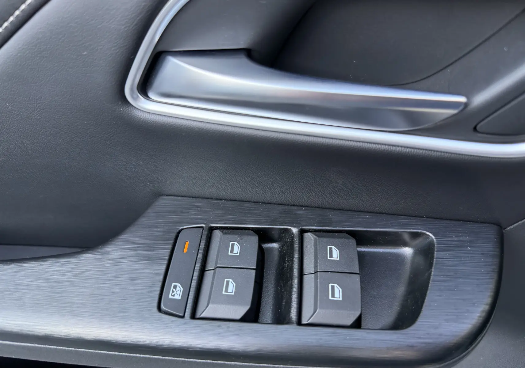 Gros plan sur la commande des vitres côté conducteur du MG ZS 1.5 L Hybrid+ 2026, finition noire intérieure.