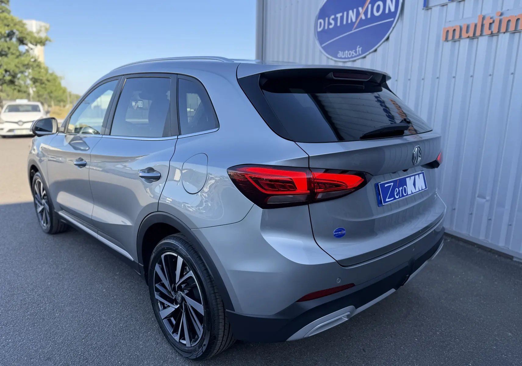 Vue 3/4 arrière droite du MG ZS 1.5 L Hybrid+ 197 ch Luxury en gris Hampstead avec feux arrière LED et jantes noires.